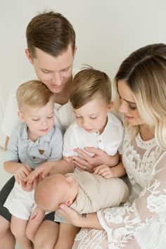 a man, woman and two boys are holding a baby