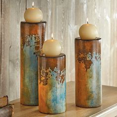 three candles sitting on top of a wooden shelf