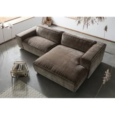 a large brown couch sitting on top of a floor next to a chair and table