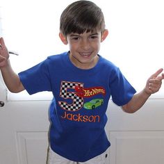 a young boy standing in front of a white door with his hands up and smiling