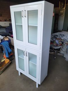 a white cabinet with glass doors in a garage