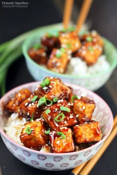 two bowls filled with tofu and rice next to chopsticks on a table