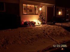 a house is decorated for christmas with lights and garlands on the front porch in the snow