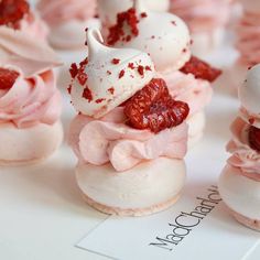 small cupcakes with white frosting and pink icing on them are sitting on a table