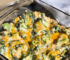 broccoli and cheese casserole in a glass dish with a spoon on the side