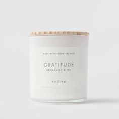 a white candle with a wooden lid that reads,'made with essential oils '