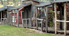 an old wooden building with lots of windows on the front and side of it, surrounded by green grass