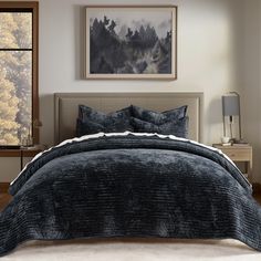 a bedroom with a large bed covered in dark blue comforter and matching throw pillows