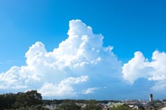 the sky is filled with white clouds and some houses are in the foreground below