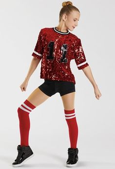 a woman in red and black soccer uniform standing with her legs spread out to the side