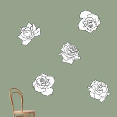 a chair and some flowers on the wall in front of a green background with white roses