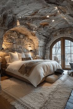 a bedroom with stone walls and an arched doorway leading to a bed that's surrounded by white fluffy rugs