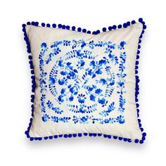 a blue and white pillow with pom poms