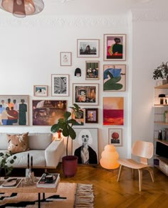 a living room filled with lots of pictures on the wall and furniture in front of it