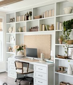 a home office with white bookcases and shelves