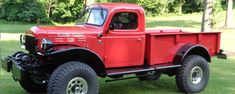 an old red truck is parked in the grass