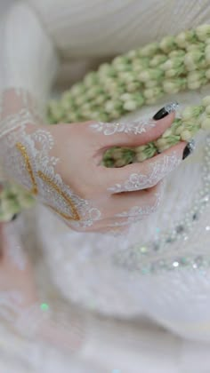 a close up of a person's hand with white lace on it and flowers