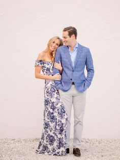 a man and woman standing next to each other in front of a white wall smiling