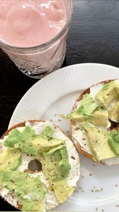 two bagels with avocado on them and a drink