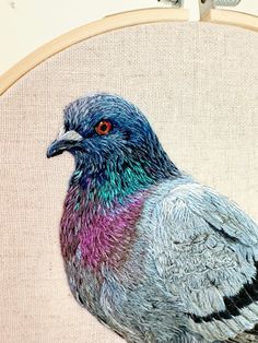 a close up of a bird on a piece of cloth with a cross stitch pattern