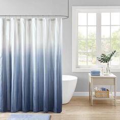 a blue and white shower curtain in a bathroom next to a bathtub with a rug on the floor