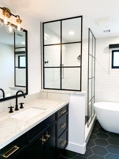 a white bath tub sitting next to a sink in a bathroom under two mirrors on the wall