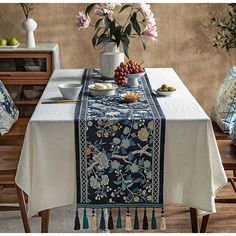 a table topped with a bowl of fruit and a vase filled with flowers on top of it