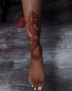 a woman's foot with a dragon tattoo on it