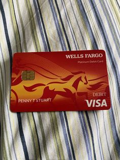 a red credit card sitting on top of a bed next to a blue and white striped pillow