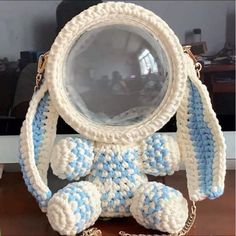 a crocheted white and blue purse with a small stuffed animal on the front