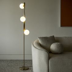 a living room with a couch and a lamp on the floor next to it in front of a white wall