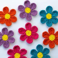 crocheted flowers are arranged on a white surface