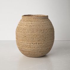 a large woven vase sitting on top of a white table next to a gray wall