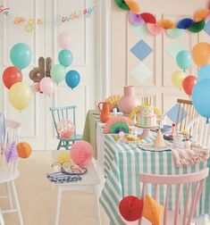 a room filled with lots of colorful balloons and cake on top of a wooden table