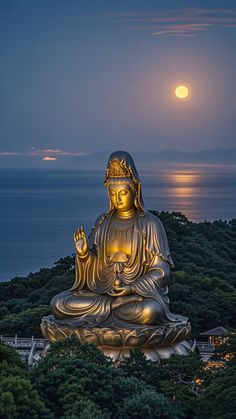 a large buddha statue sitting on top of a lush green hillside next to the ocean