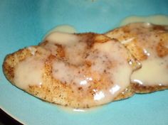 two pieces of chicken covered in gravy on a blue plate