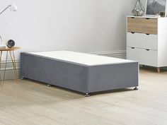 a bed sitting on top of a wooden floor next to a white wall