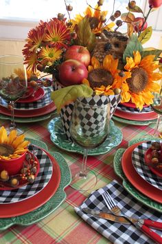 the table is set for thanksgiving dinner with sunflowers and apples