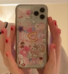 a woman holding up her phone case with stickers on it