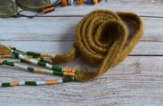 a brown rope with green and white beads on it next to some other bead items