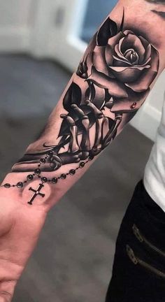 a person with a tattoo on their arm holding a cross and a rose in the middle