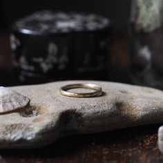 a gold ring sitting on top of a rock next to other rocks and shells in the background