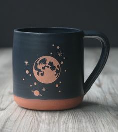 a black and brown coffee mug sitting on top of a wooden table