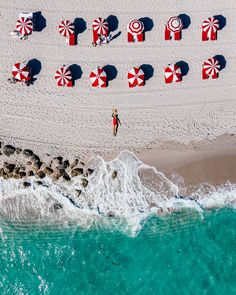 an aerial view of the beach with umbrellas and people walking on the sand near the water