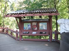 a small red structure with pictures on it in the middle of some trees and rocks