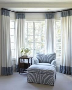 a zebra print chair and ottoman in front of a large window with blue drapes