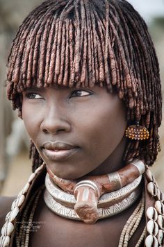 an african woman with braids on her head and wearing large necklaces around her neck