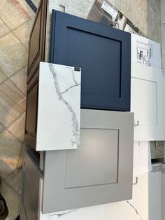 some white and blue cabinets in a room with marble flooring on the walls, and other cabinetry