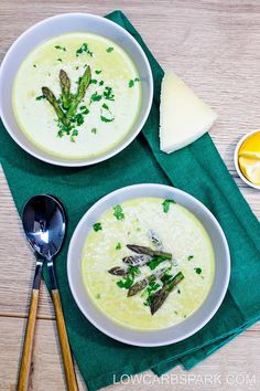 two bowls of soup with asparagus, cheese and parsley on the side