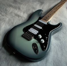 an electric guitar sitting on top of a white sheet